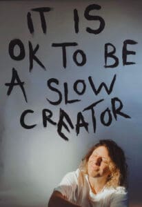 its ok to be a slow creator painted on wall above woman